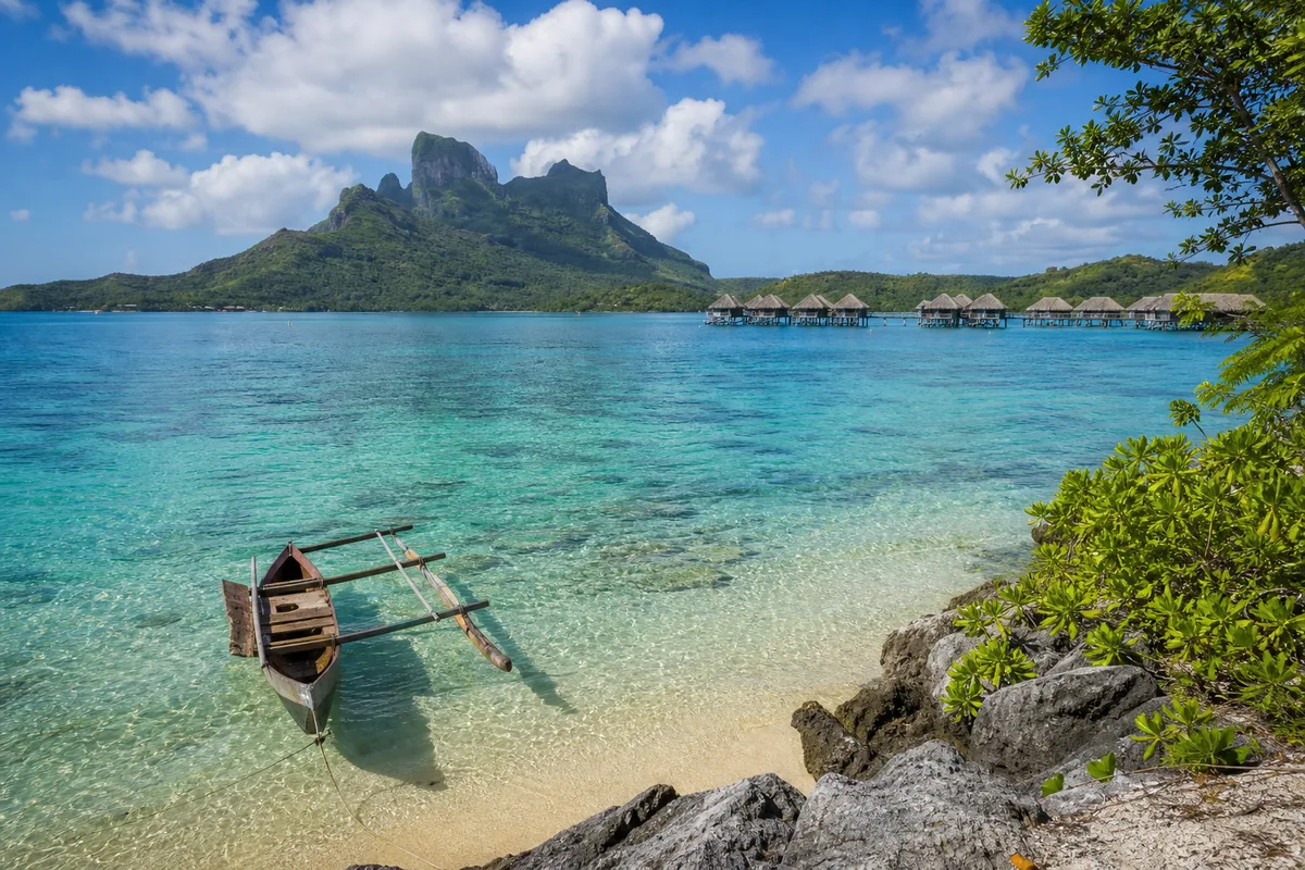Lagon turquoise de Polynésie française avec bungalows sur pilotis et montagne volcanique en arrière-plan